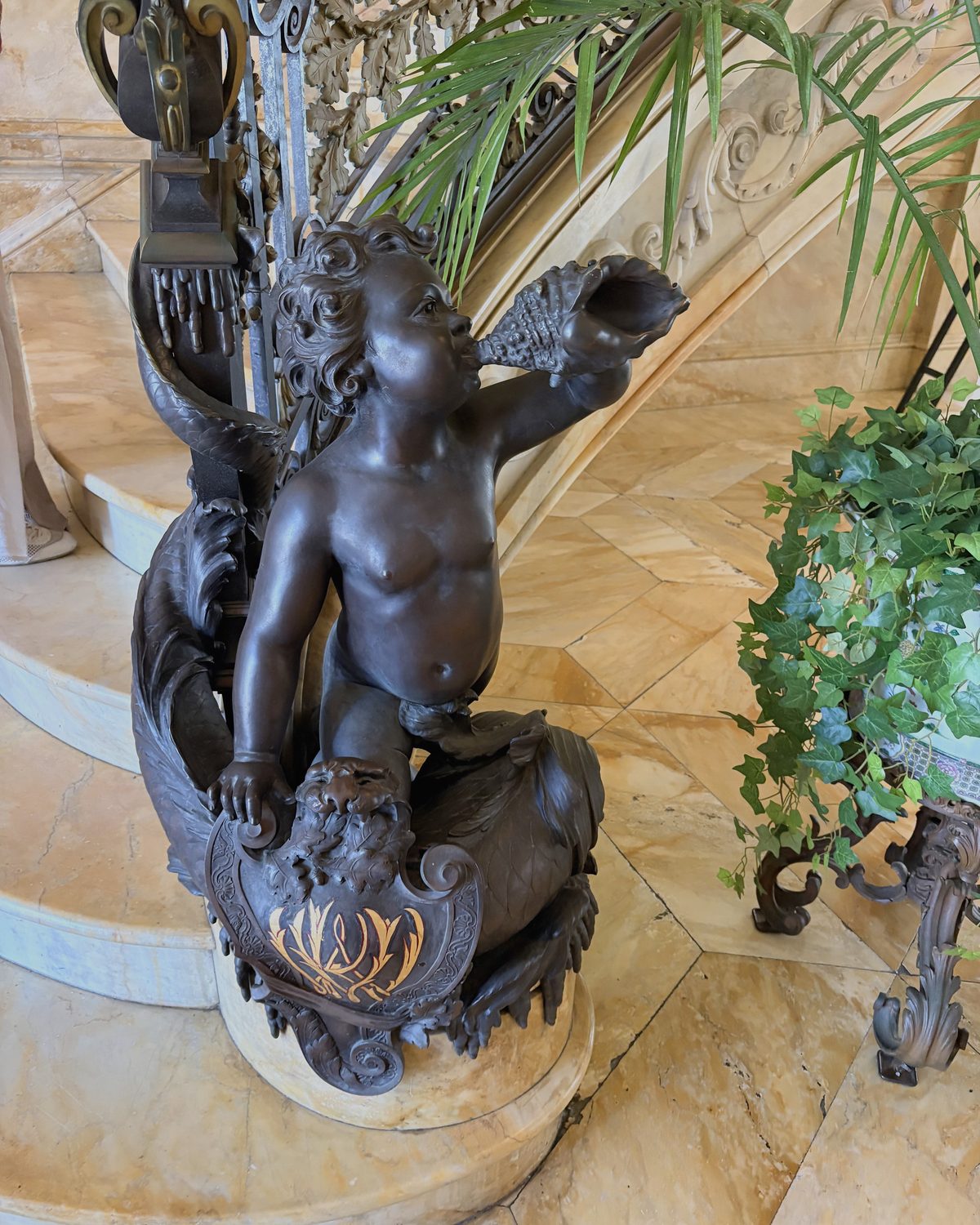 A bronze putto astride a dolphin at the foot of a marble staircase