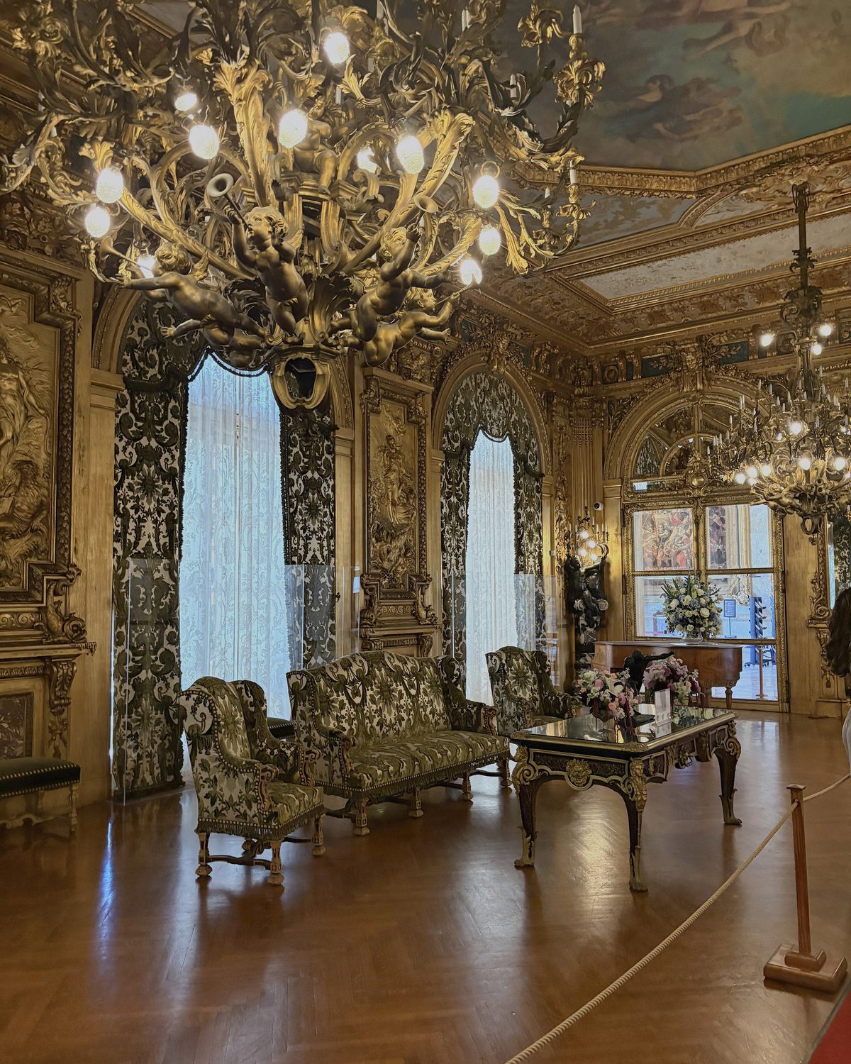 A gilt salon with chandeliers, silk curtains and painted ceiling