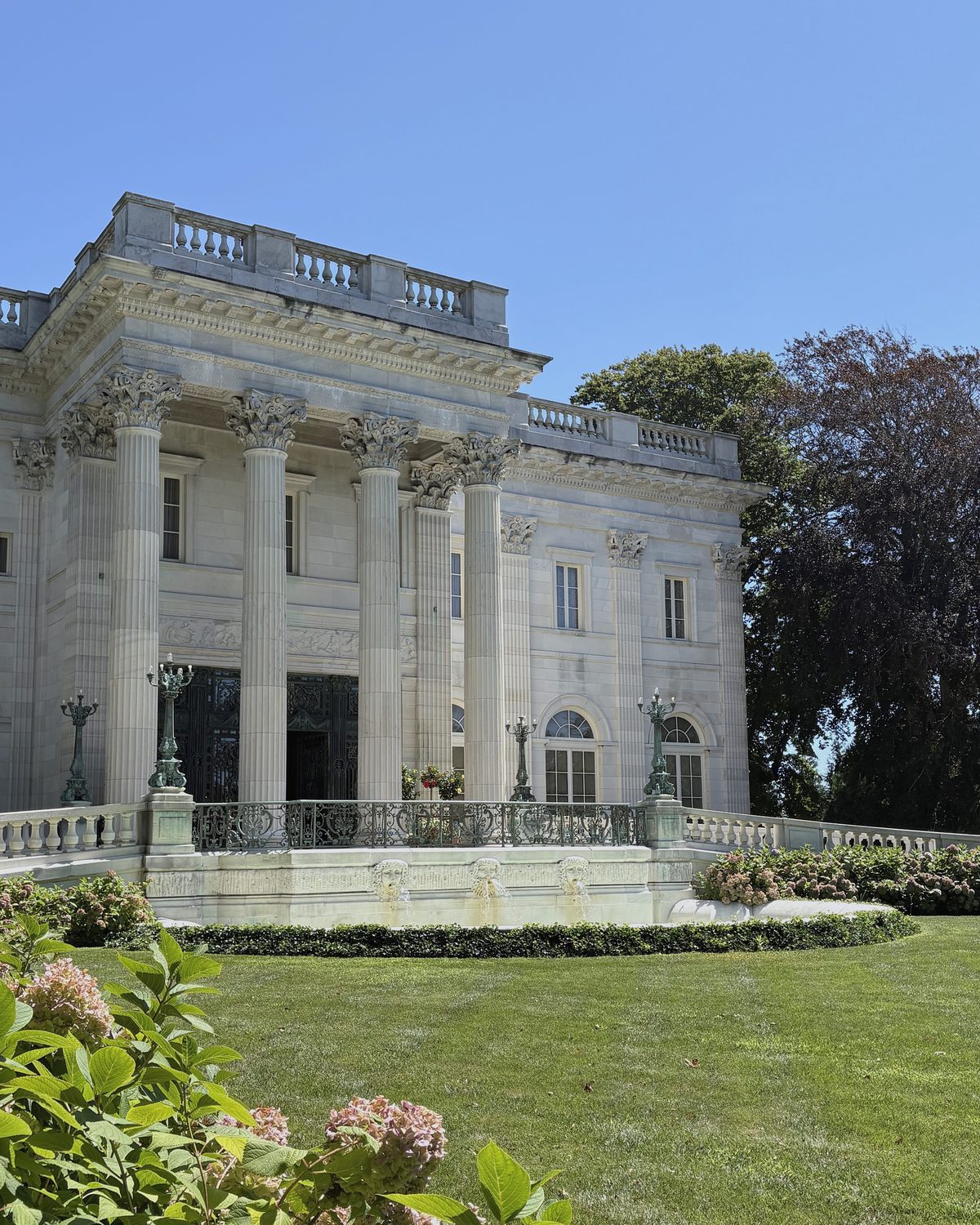 Marble House behind hydrangeas, its portico columns in full sun